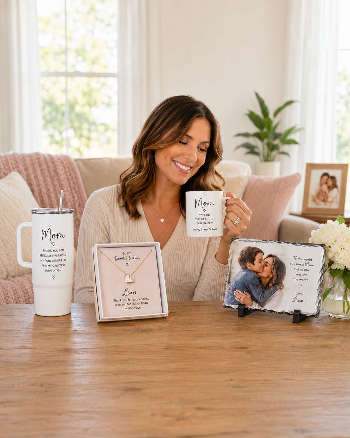 Smiling mom holding a personalized Mom mug beside a custom tumbler, engraved necklace, and photo memorial slate from Wynn’s Witty Works Gifts for Mom collection.
