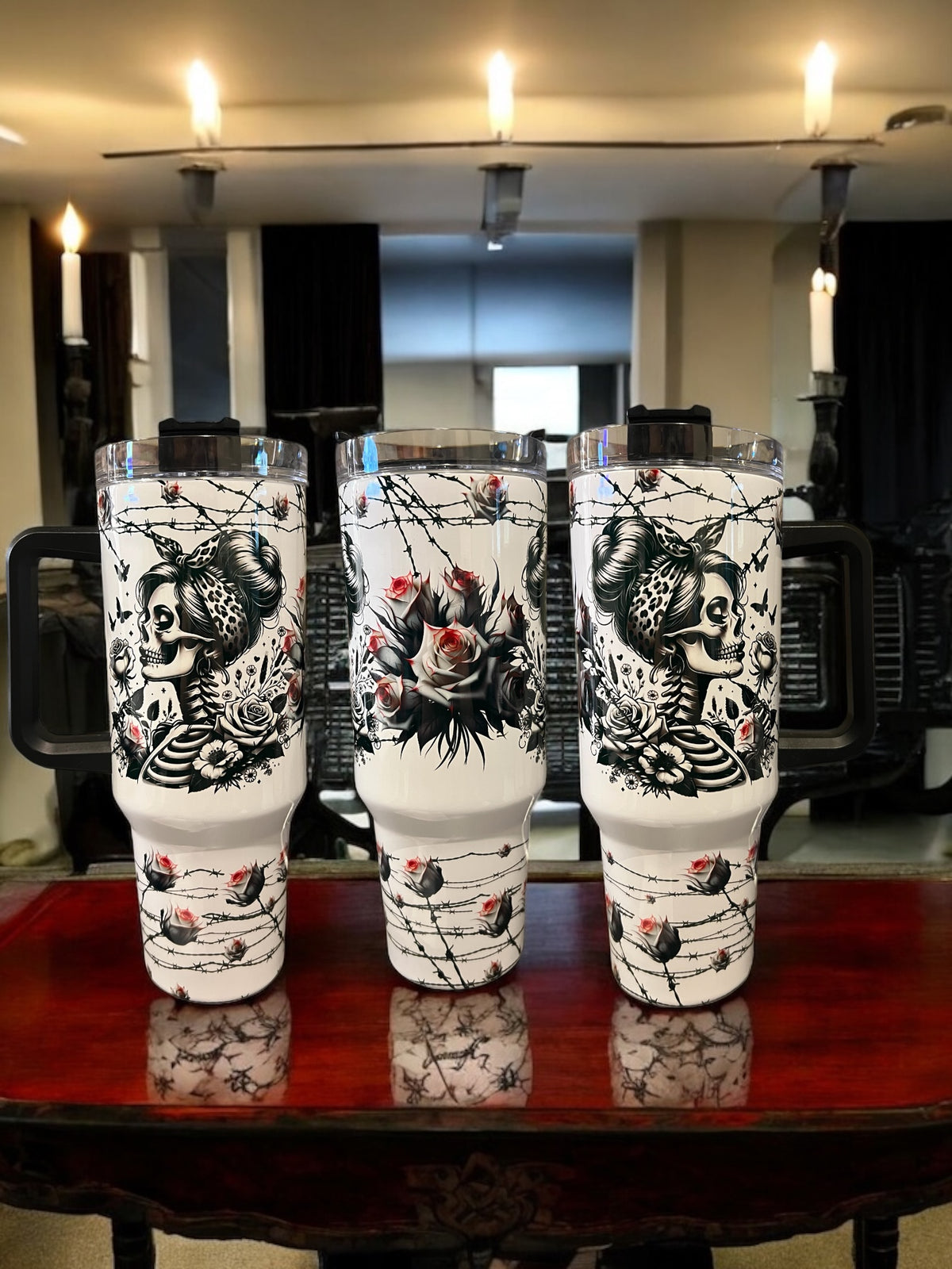 Three tall, white tumblers with black and red designs on a wooden table.