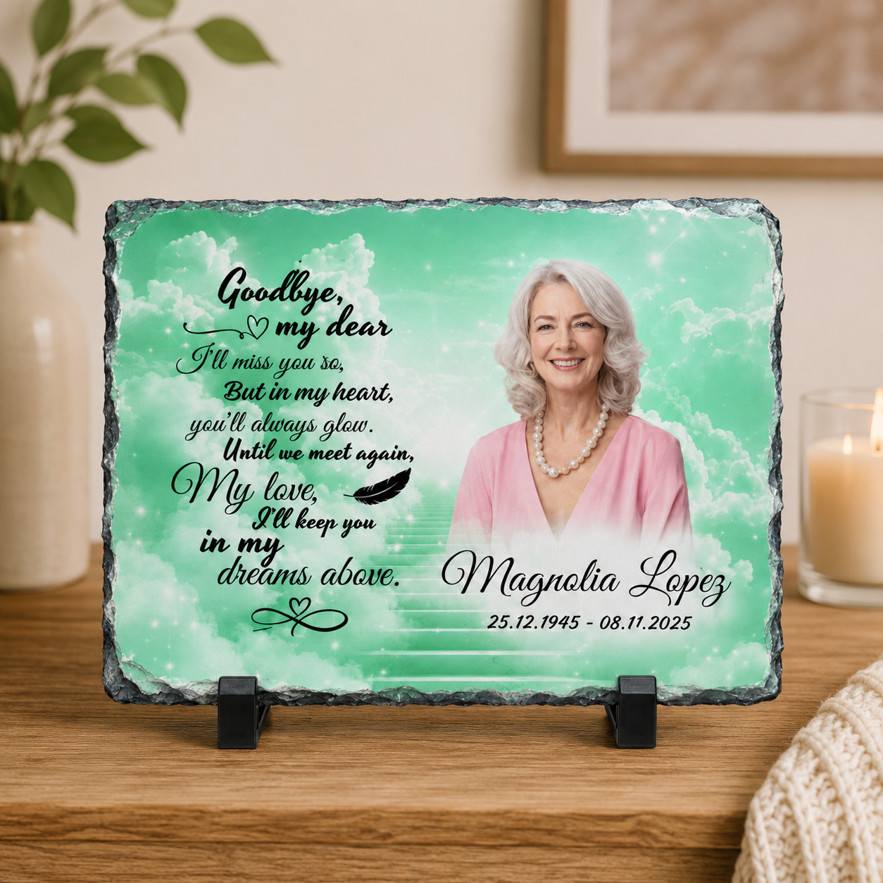 Personalized memorial slate plaque on a wooden stand, featuring a photo of a smiling woman, a teal watercolor background, and a remembrance poem. The plaque is displayed on a wooden table with a lit candle and home decor in the background.