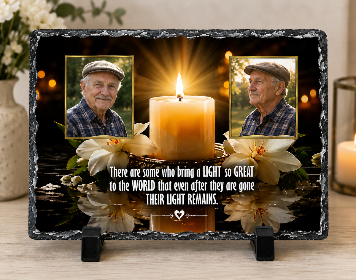 A rectangular memorial-style photo plaque or print on a black stand, displayed on a wooden table in a softly lit room. The design shows two portrait photos, a glowing candle, white flowers, and a quote about a light left behind.