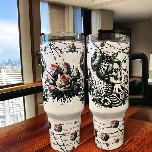 Two tumblers with artistic designs on a wooden surface near a window with a cityscape view.